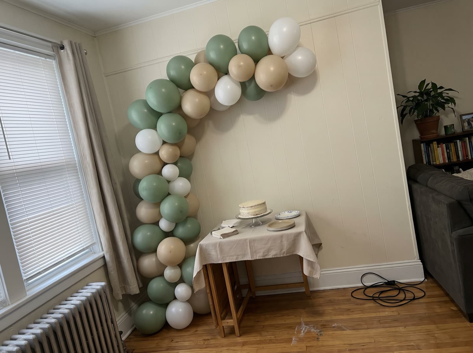 Half balloon arch over a cake table in a small apartment